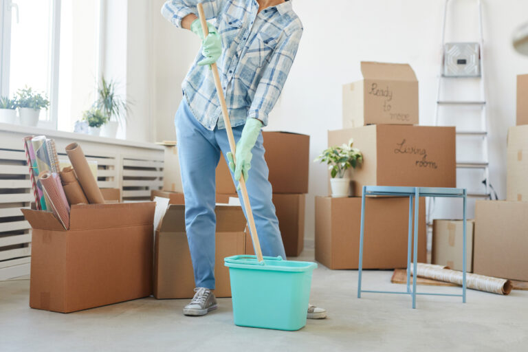 Woman holding a mop with moving boxes behind her